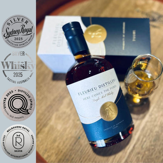 Fleurieu Distillery whisky bottle with a glass and four silver medals on a wooden surface